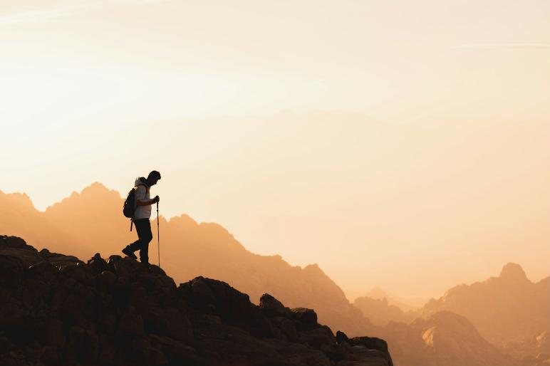 A hiker walking along a rocky ridge at sunrise