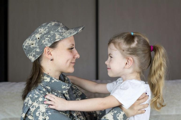 A mother in uniform hugging her young daughter